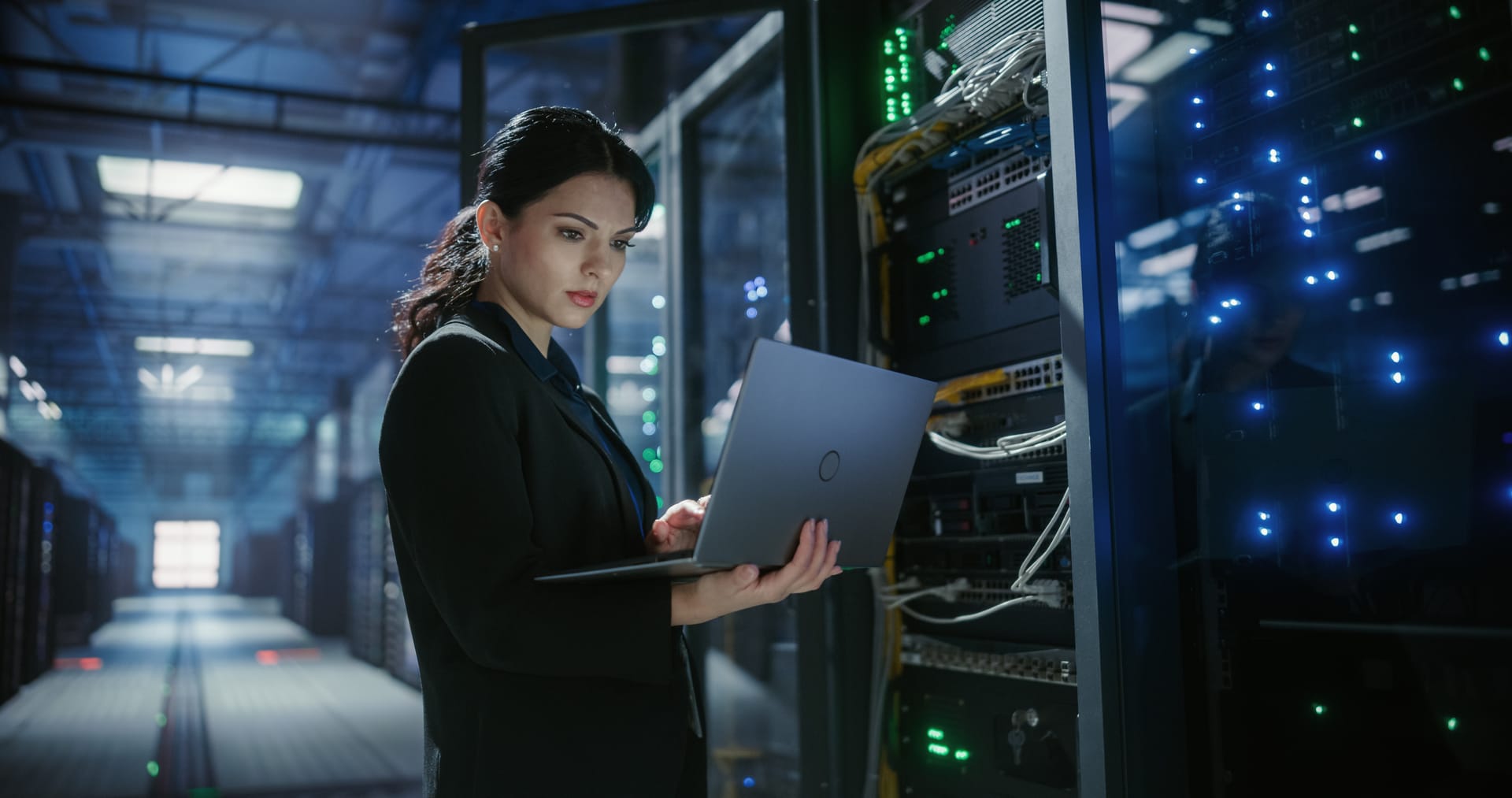Engineer checking a server rack with a laptop in a data center