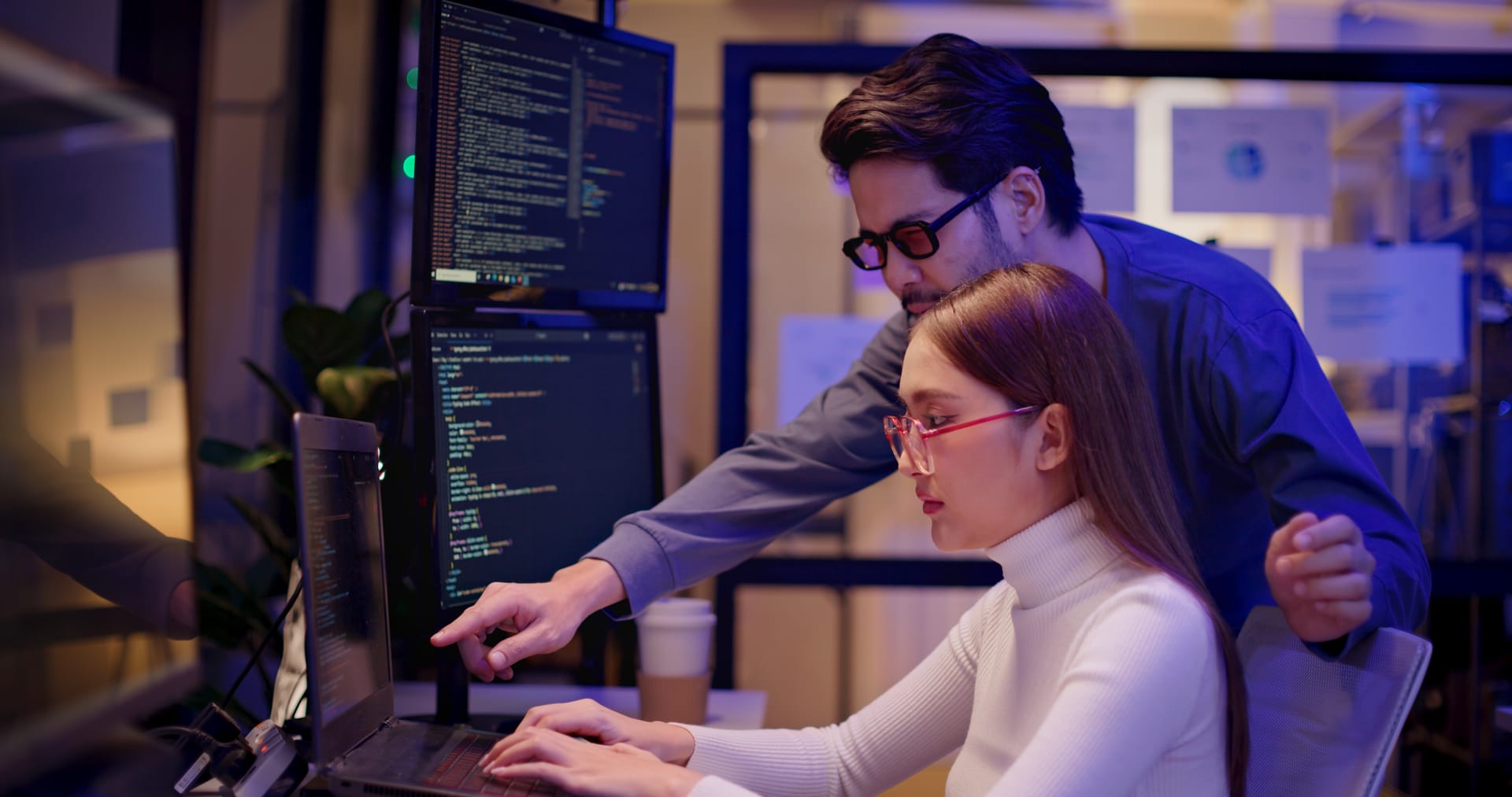 Two software engineers reviewing code together at a workstation