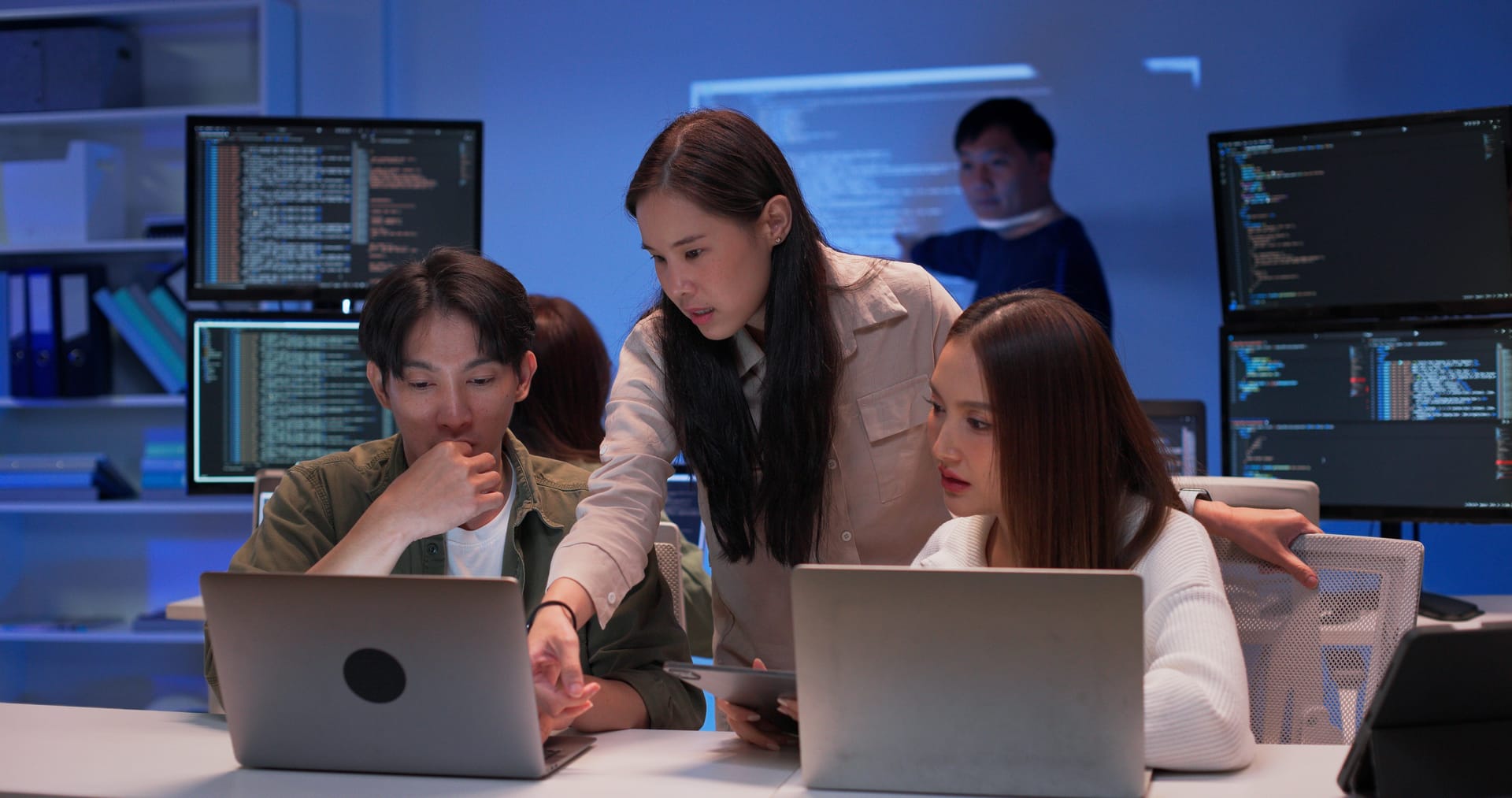 Engineering team working together in a blue-lit office