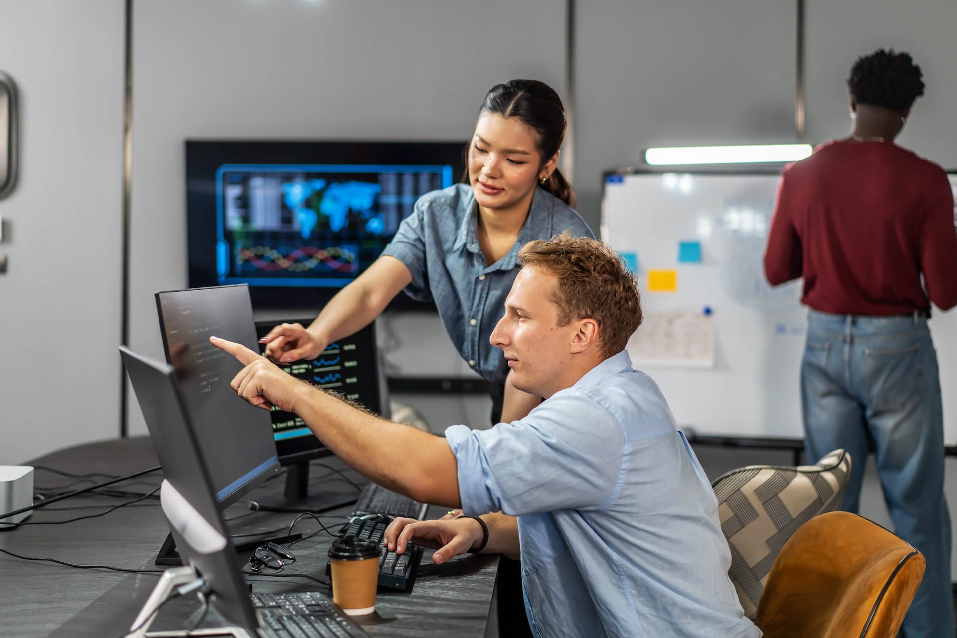Engineers pointing at data on a monitor in an open office