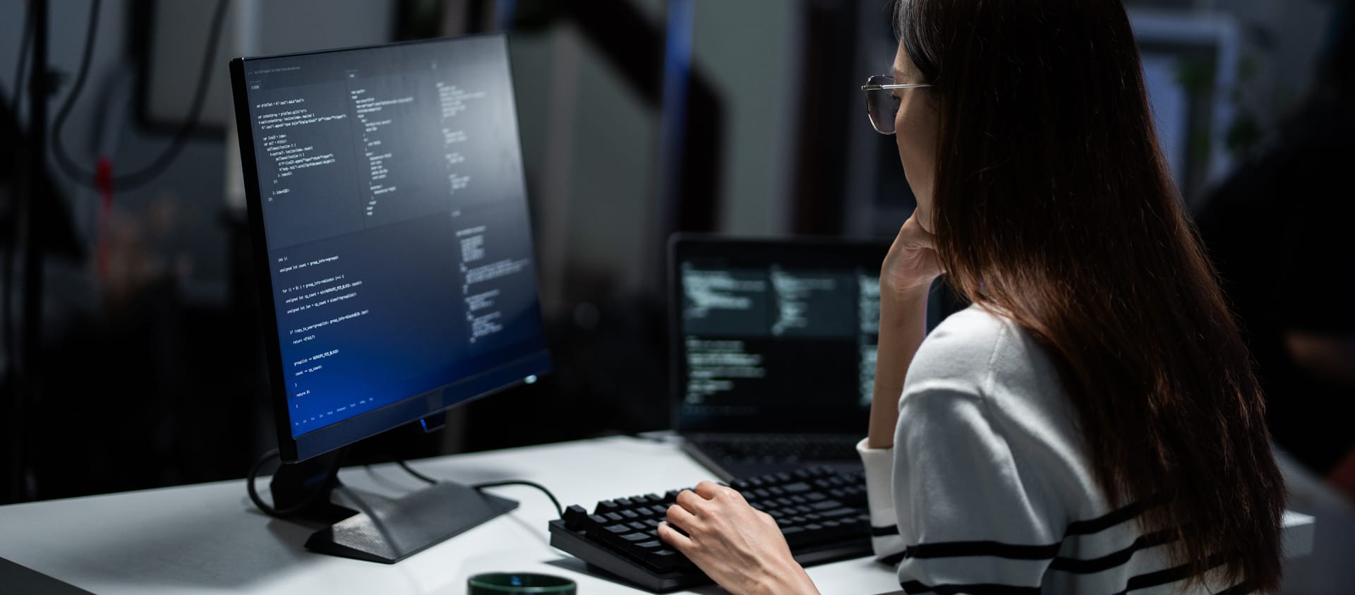 Engineer working at a monitor of code in a dark office