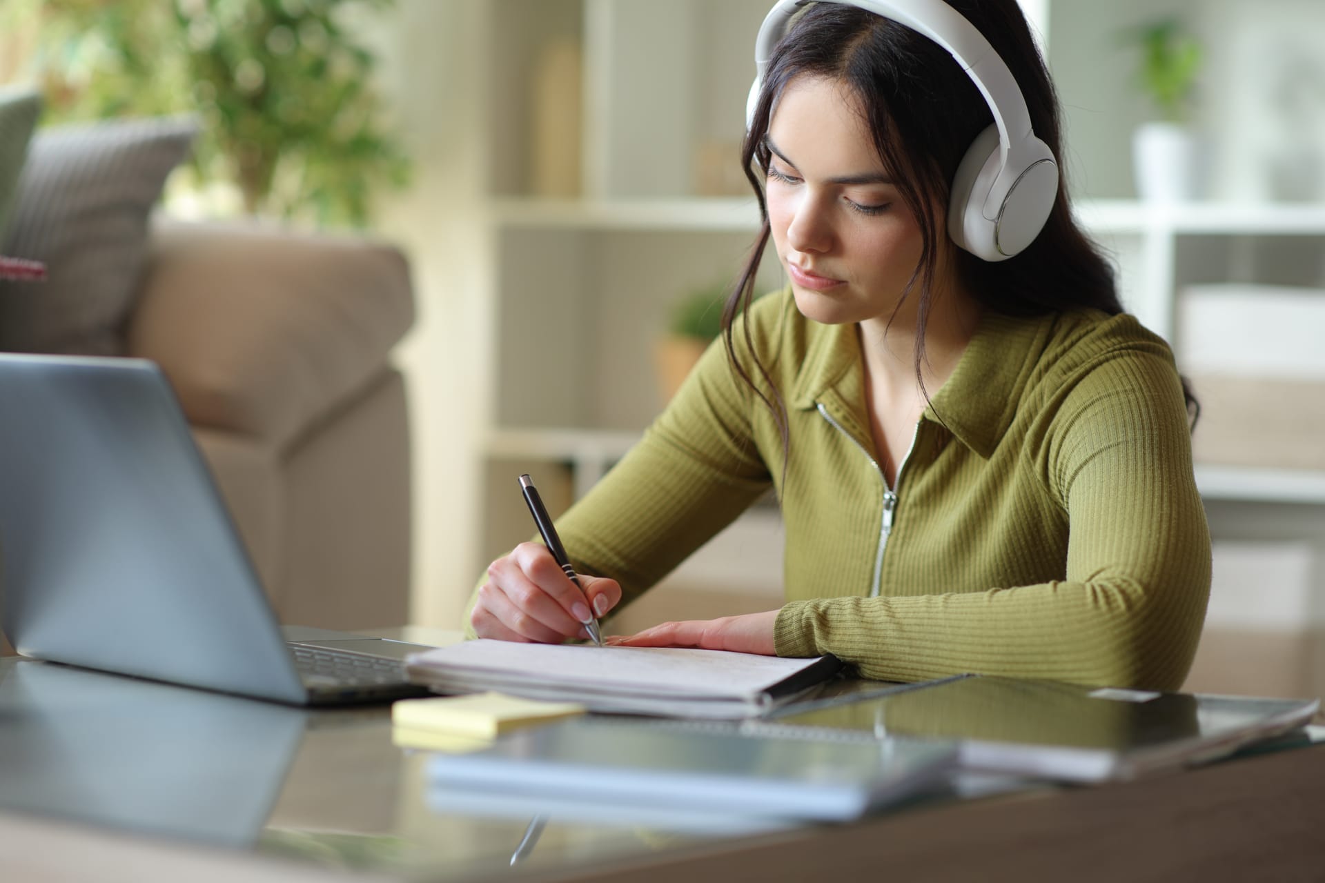 Student with headphones taking notes during an online lesson