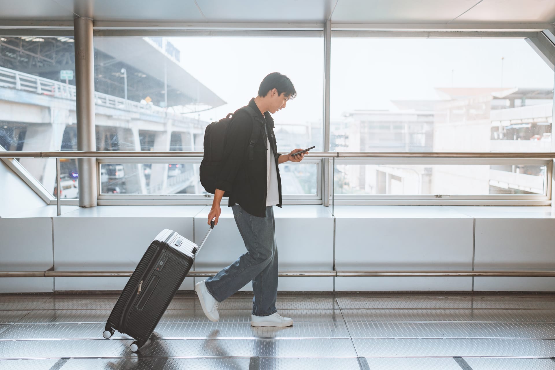 Traveler with a suitcase checking his phone in an airport terminal